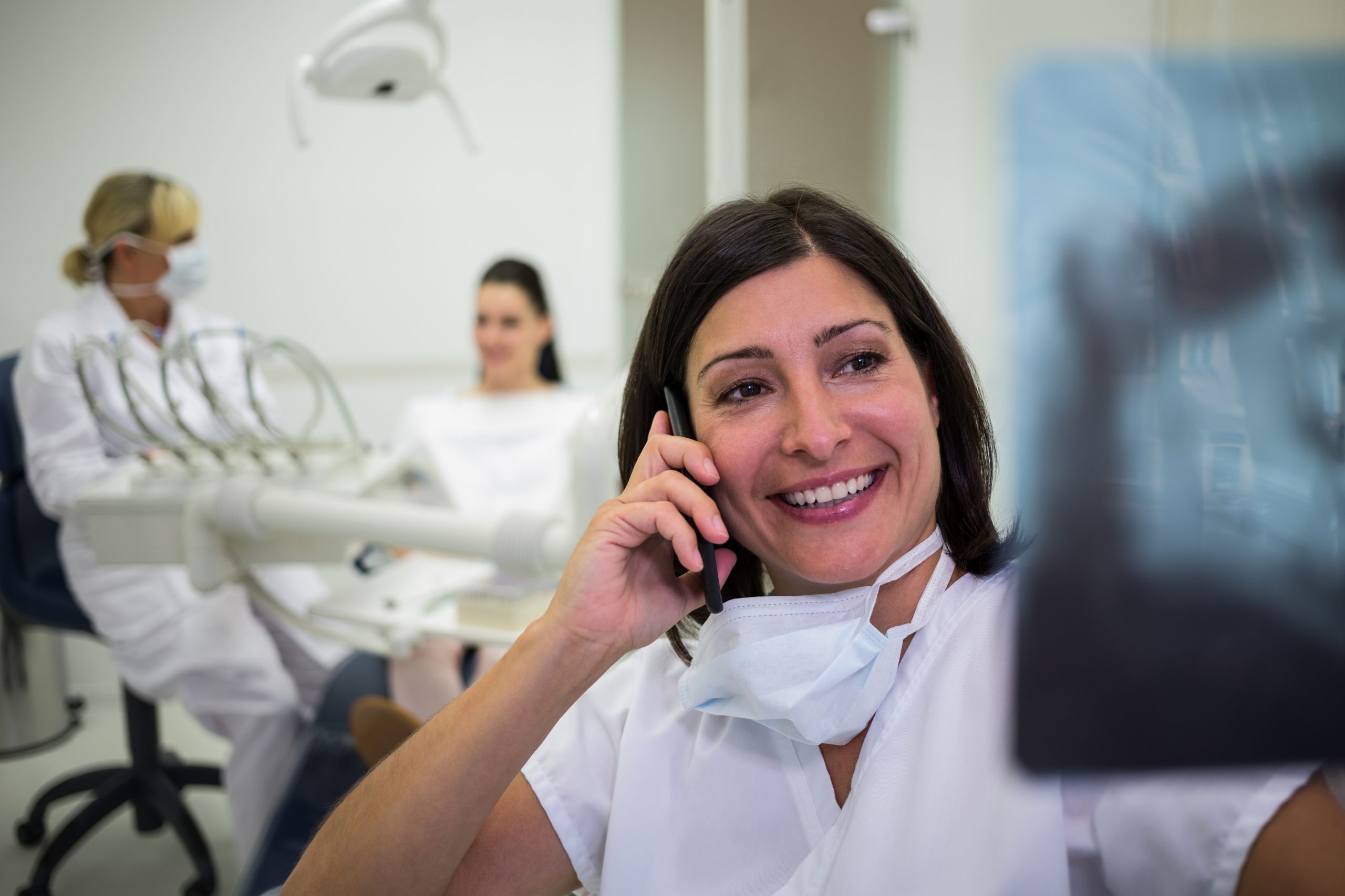 dentist checking x ray report while talking mobile phone scaled