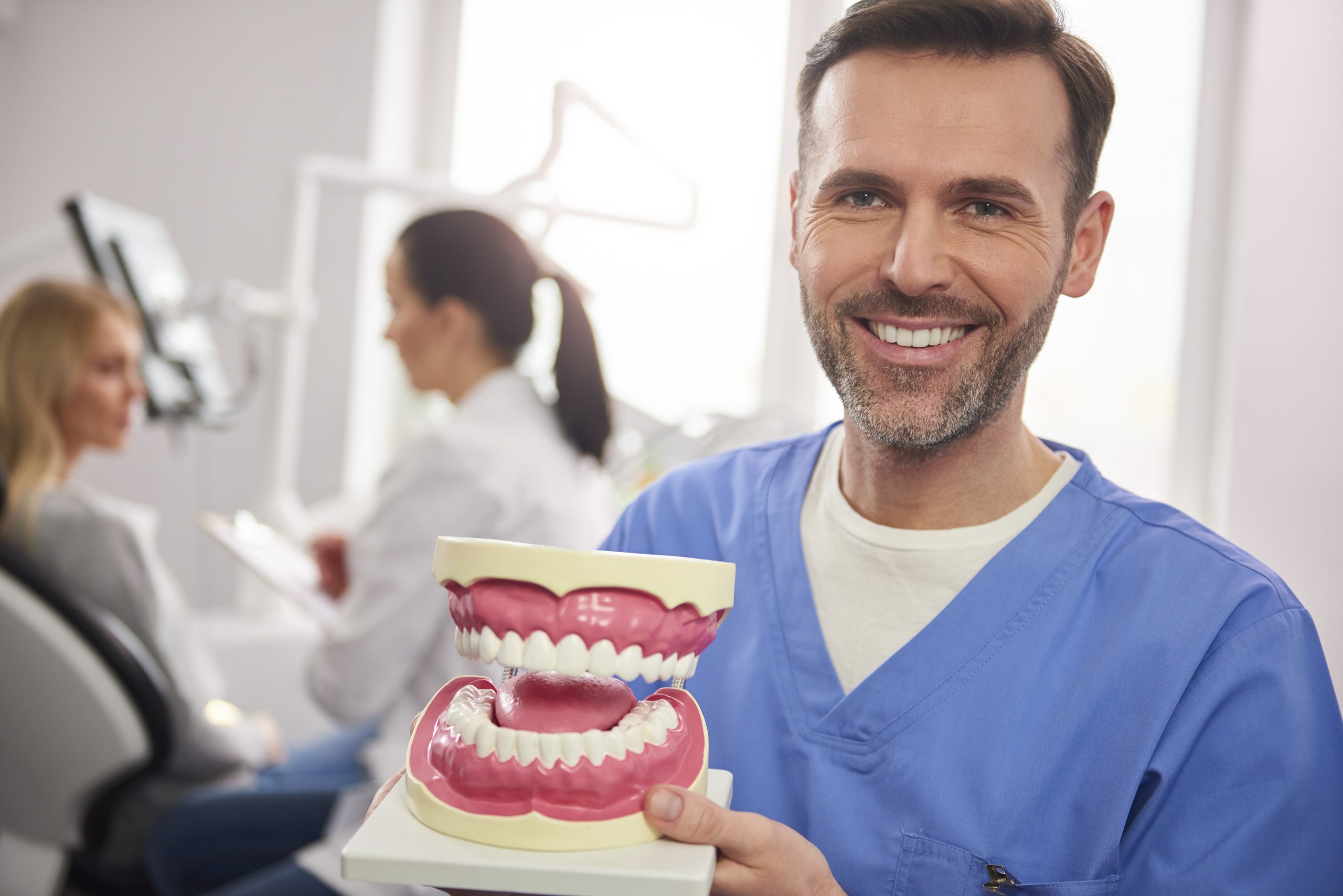 smiling dentist showing artificial dentures scaled